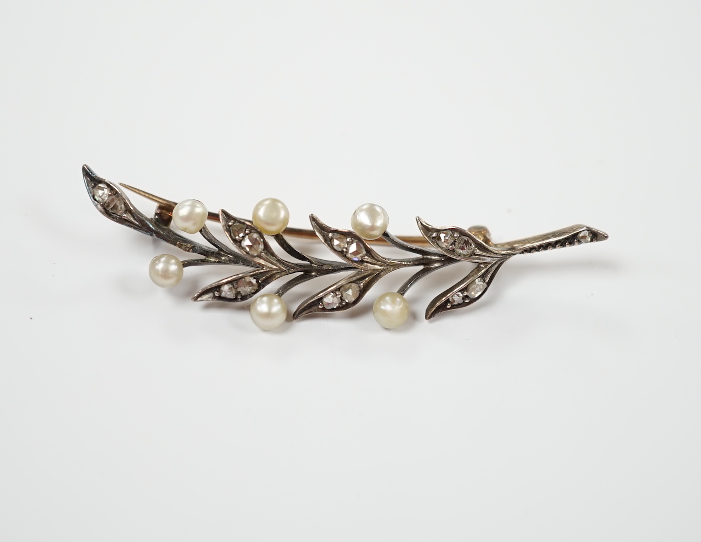 An early 20th century yellow metal, cultured pearl and rose cut diamond set foliate spray brooch, 58mm, gross weight 5.8 grams.